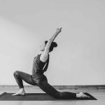 Black and white, image of a yoga teacher posing on matt, with soft lighting and a side angle.
