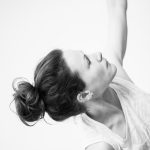 Black and white, closely cropped image of a yoga teacher looking skyward, with soft lighting and minimal detail.