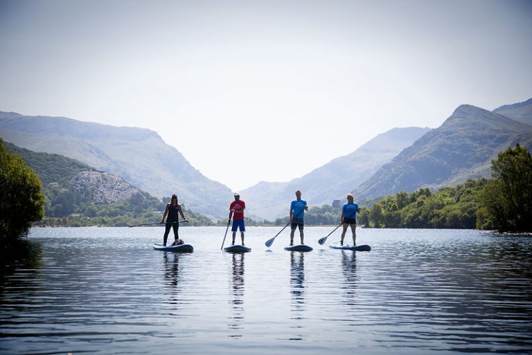 Stand Up Paddle boarders on a lake in Wales Snowdonia in the distance