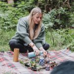 Forest retreat pouring herbal tea on a picnic blanket